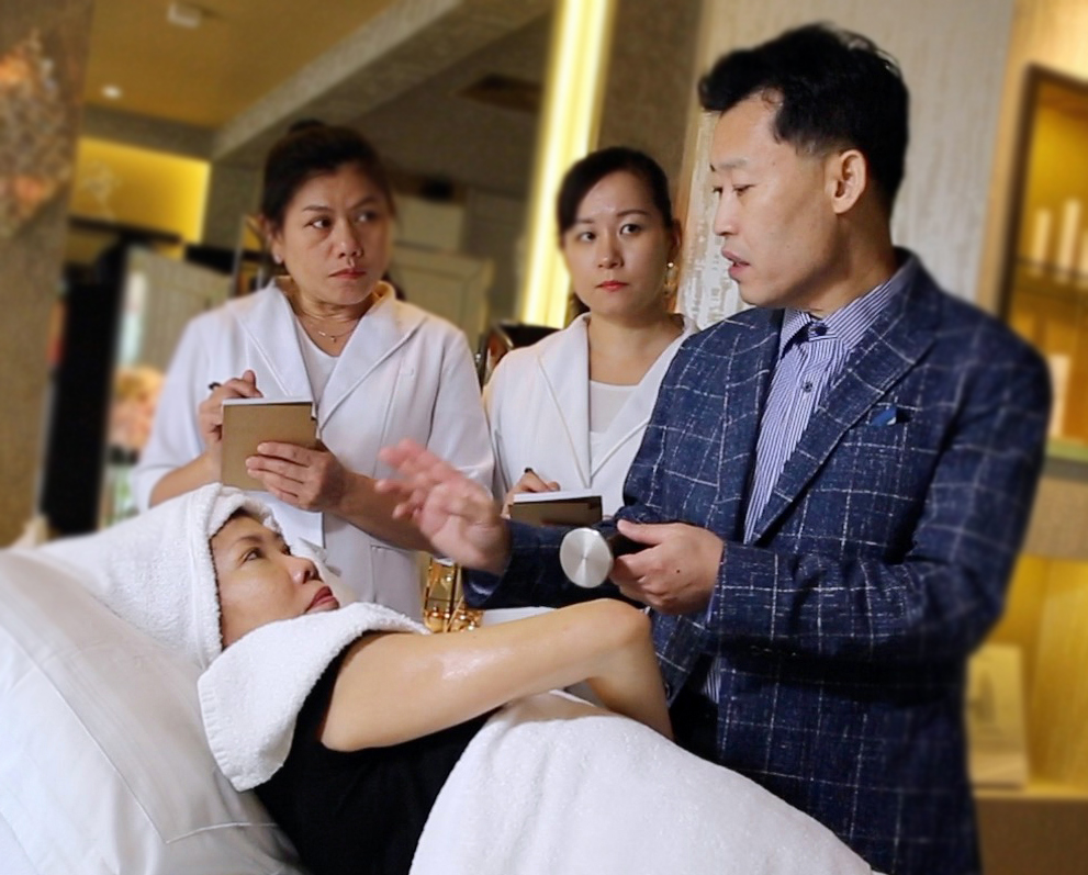 A visiting doctor demonstrating a treatment device to note-taking Frances therapists